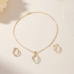 Minimalist gold necklace and earring set with geometric textured pendant.